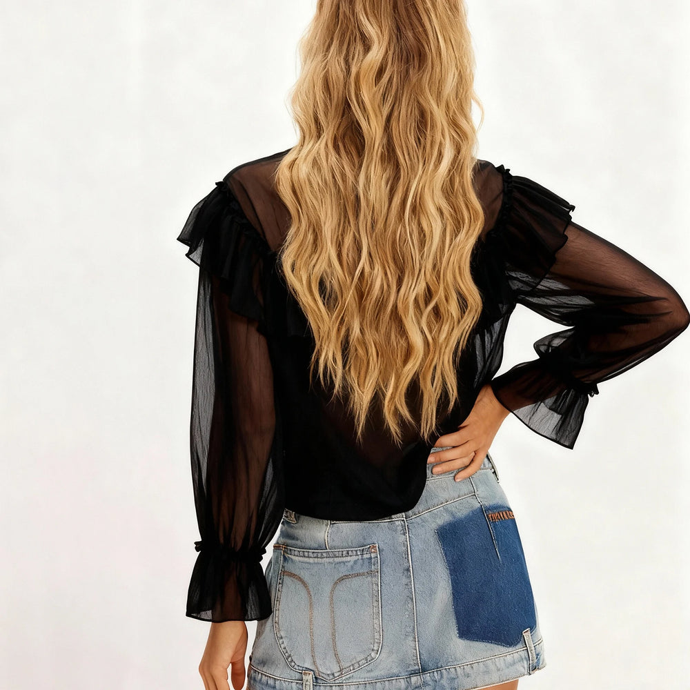 Person wearing a black sheer blouse and denim skirt on a white background