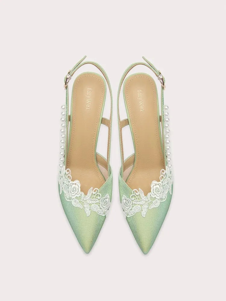 Pair of light green high heels with lace detailing on a white background