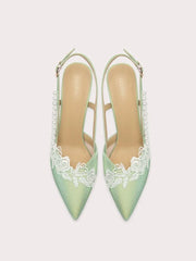 Pair of light green high heels with lace detailing on a white background