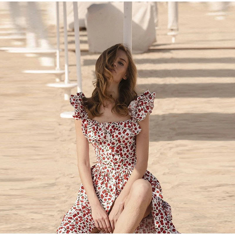 Woman in a floral dress sitting on a wooden floor with a neutral background