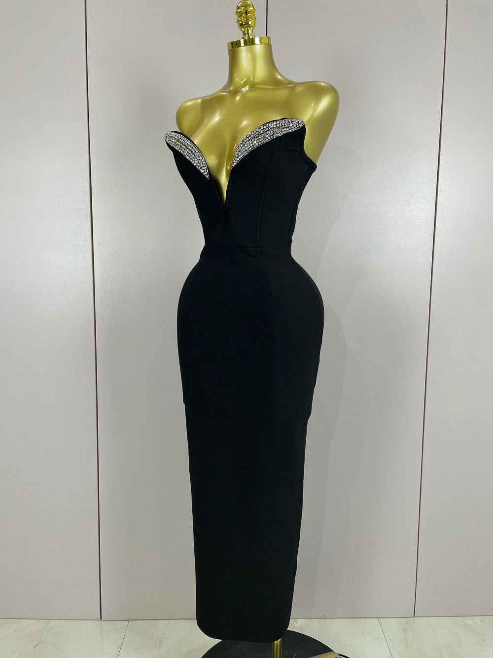 Black evening gown with beaded neckline on a mannequin against a plain background