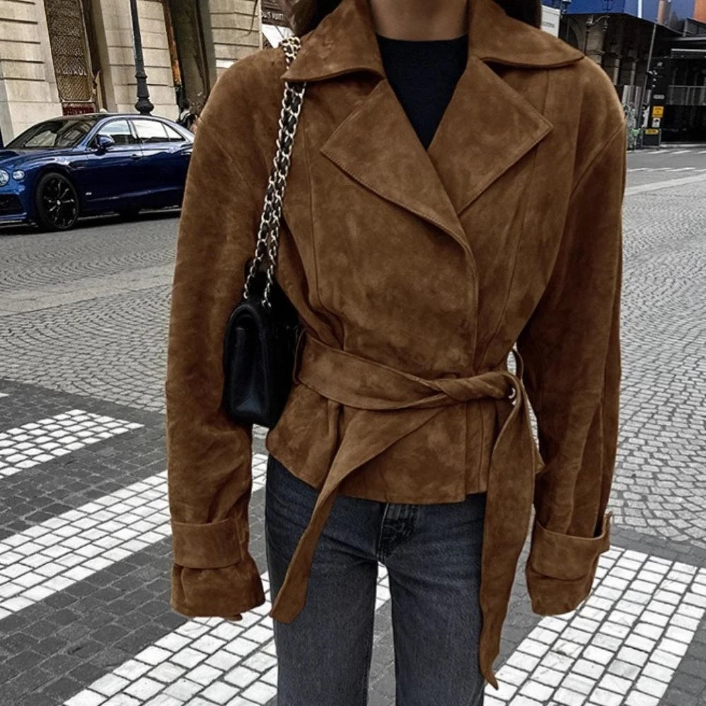 Person wearing a brown suede coat on a city street