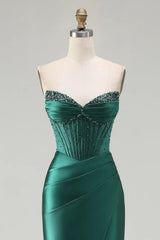 Green evening gown with beaded details on a mannequin against a gray background