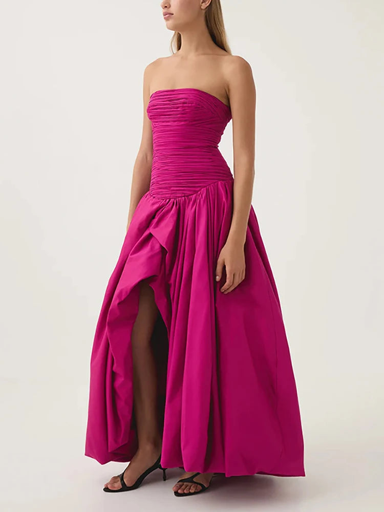 Woman wearing a strapless pink gown with a high-low hem on a white background