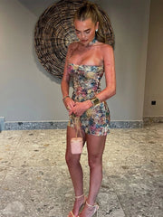 Woman in a floral strapless dress holding a pink handbag indoors.