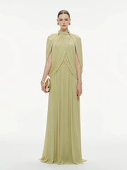 Woman wearing a light green evening gown with a cape on a white background