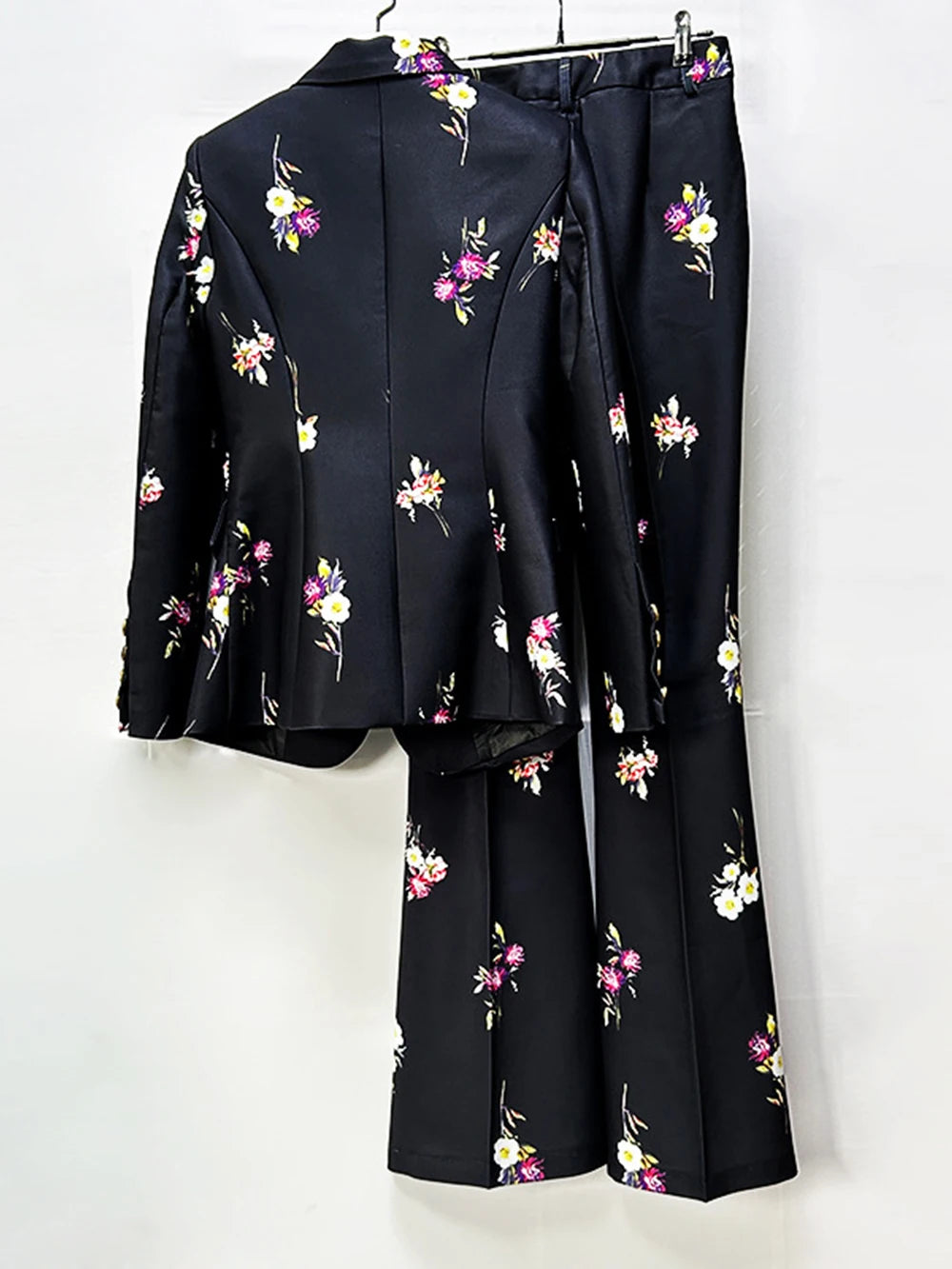 Back view of a black floral print blazer and flare pants suit on a hanger.