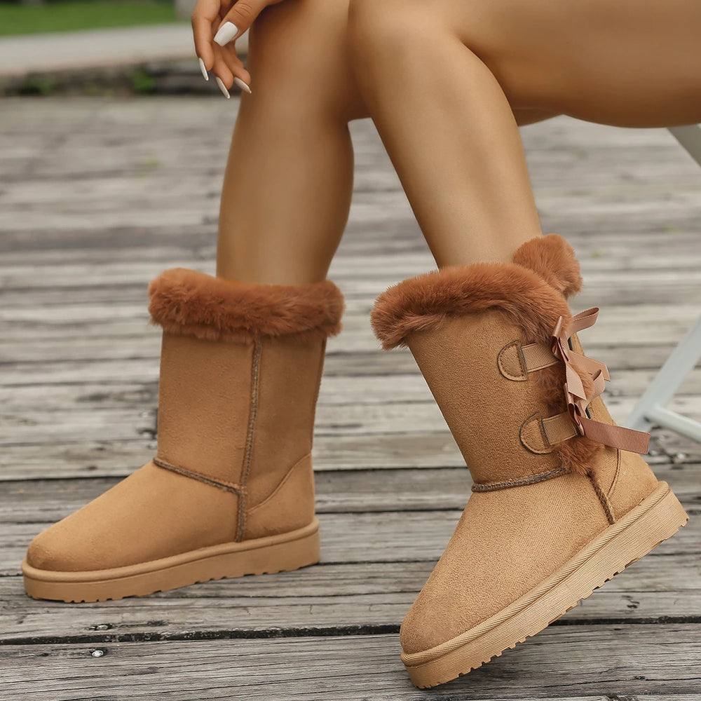 Tan winter boots with fur trim on a wooden floor