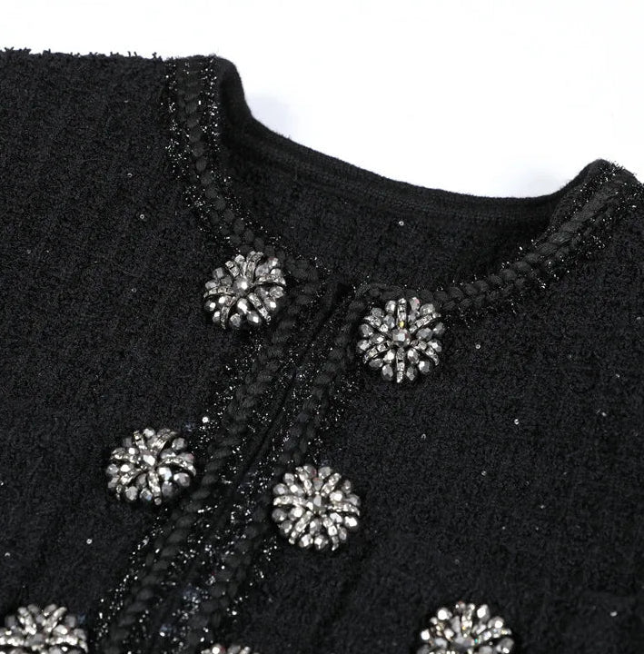 Black textured garment with decorative buttons on a white background