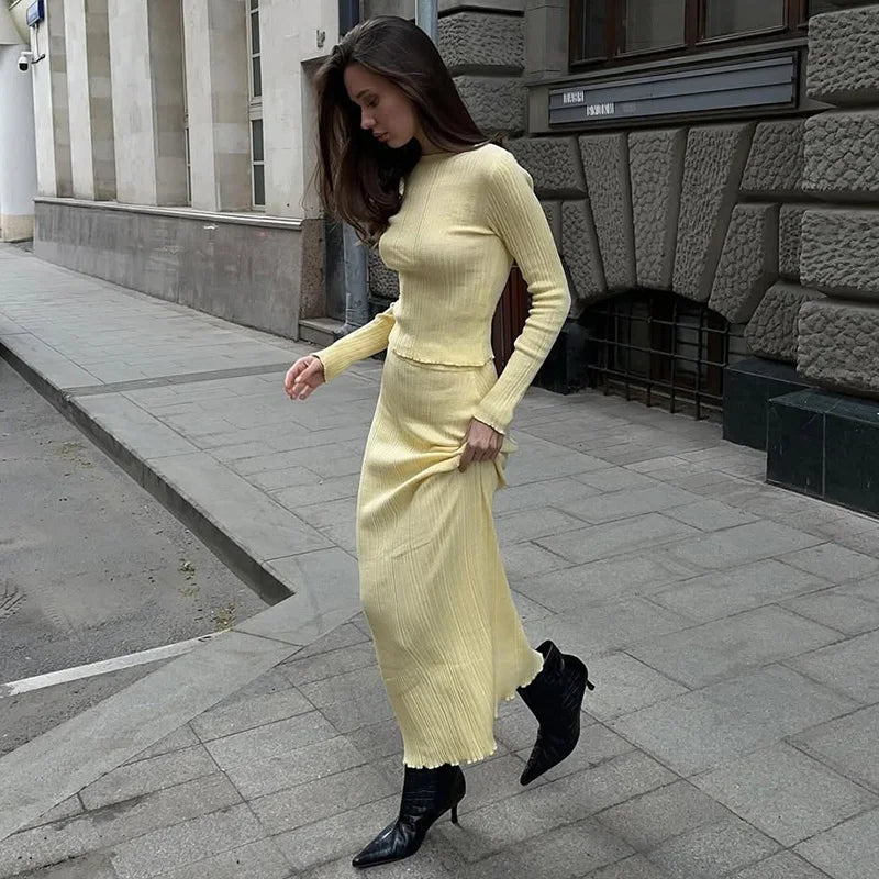 Woman in a yellow knit dress walking on a city street.