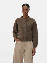 Woman wearing a brown cardigan and beige pants on a white background