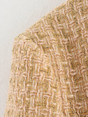 Close-up of a textured fabric with gold and beige pattern on a light gray background