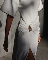 White dress with a decorative brooch on a neutral background