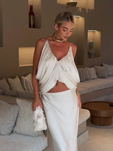 Woman in a white dress standing in a modern living room.