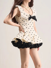 Woman wearing a polka dot dress with a black bow on a plain background