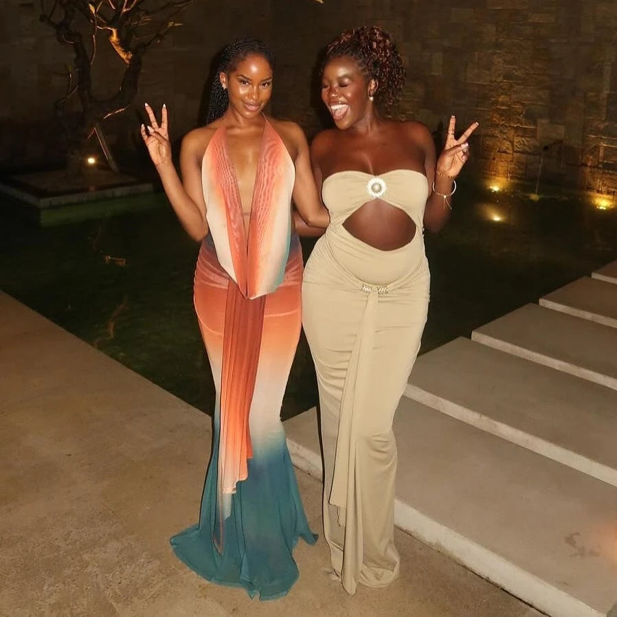 Two women in elegant evening gowns standing outdoors at night.