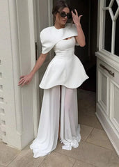 Woman in a white dress with puffed sleeves and sheer panels standing in a doorway.