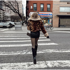 Person crossing a city street wearing a leopard print coat.