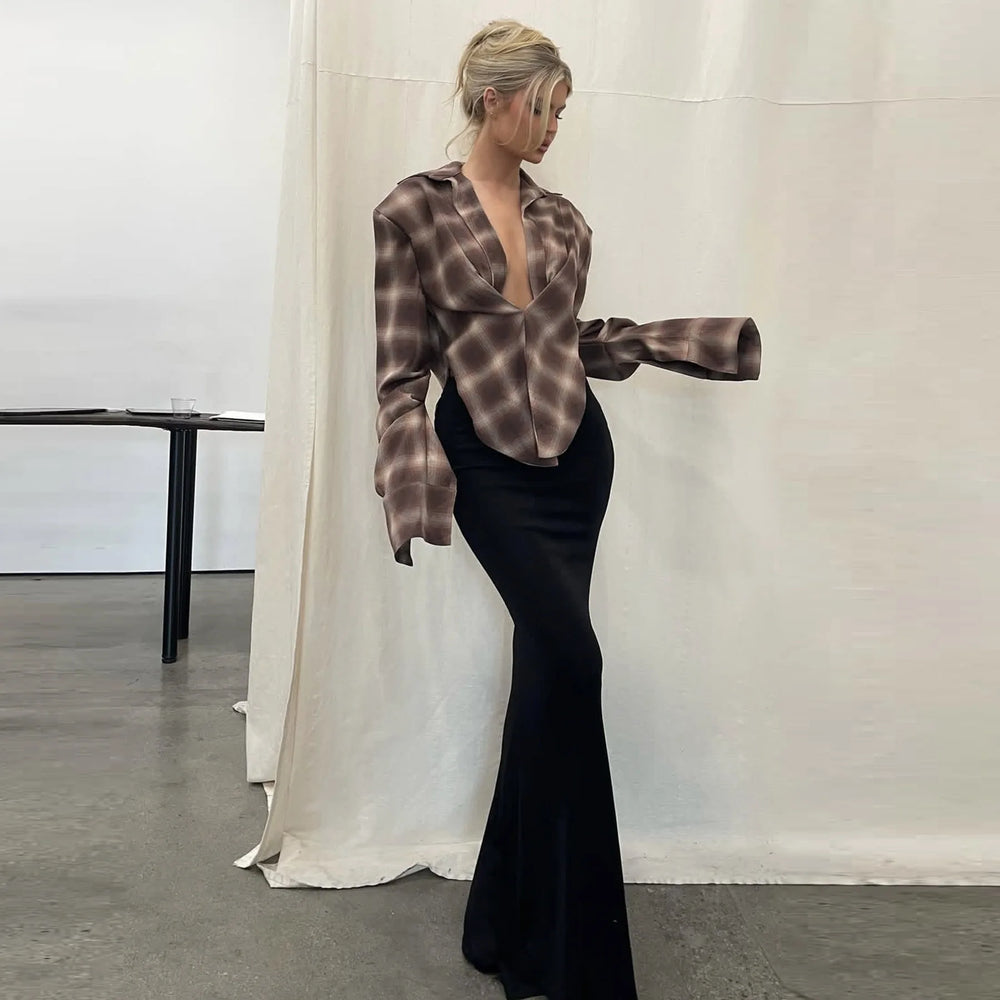 Woman wearing a plaid blouse and black pants in an indoor setting