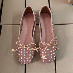 Top-down view of beige mesh ballet flats featuring crystal embellishments and bows.