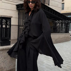 Person wearing a black outfit with ruffled details in an urban setting