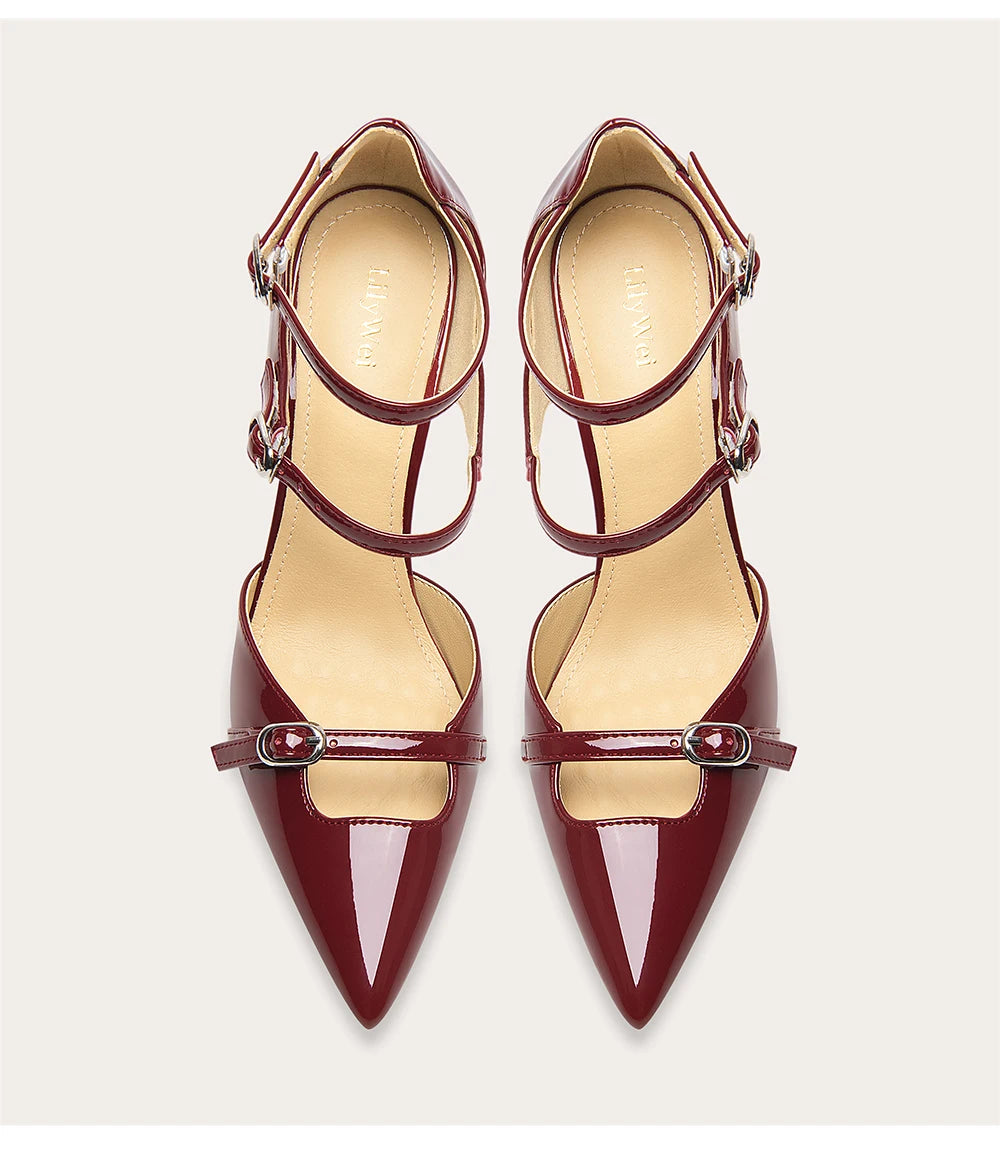 Pair of maroon high-heeled shoes with thin straps on a light beige background