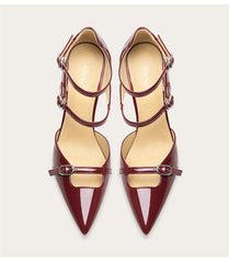 Pair of maroon high-heeled shoes with thin straps on a light beige background