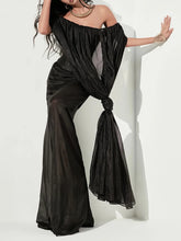 Woman wearing a black off-shoulder outfit with wide-leg pants against a white background