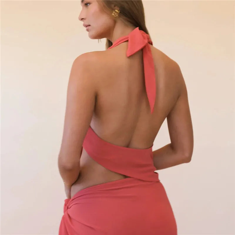 Woman wearing a coral dress with a halter neck design on a plain background