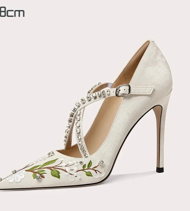 High-heeled shoe with floral design and embellishments on a white background