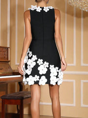 Black dress with white floral details worn by a model in an elegant room.