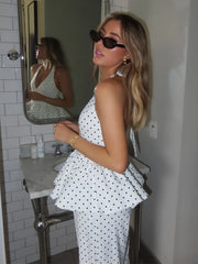 Woman in a polka dot dress standing in a bathroom mirror.