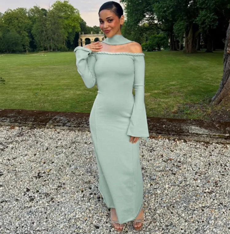 Woman in a light green off-shoulder dress standing outdoors with trees and grass in the background