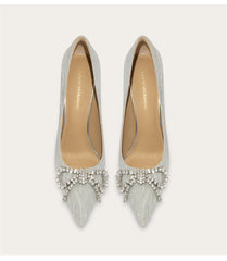 Pair of silver pointed-toe shoes with embellishments on a light gray background