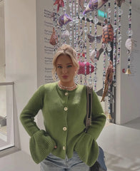 Woman wearing a green cardigan with decorative fish and beads in the background