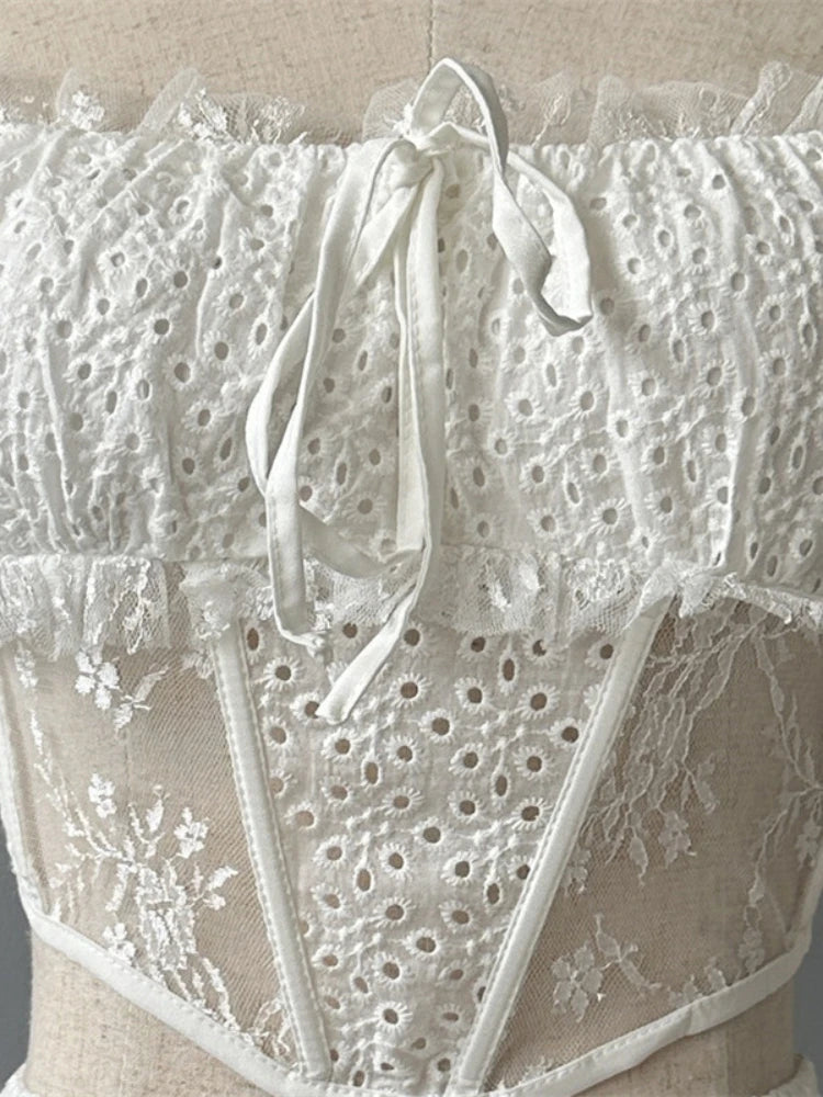 Close-up of a white lace garment with floral patterns on a neutral background