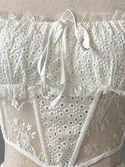 Close-up of a white lace garment with floral patterns on a neutral background
