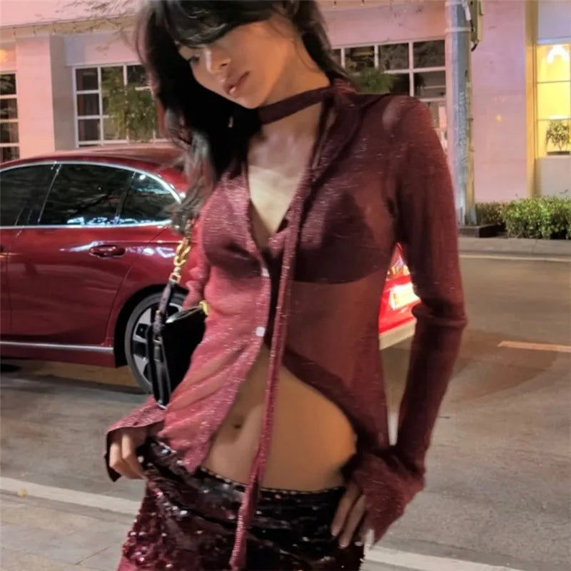 Woman in a burgundy hoodie and sequin skirt standing in front of a red car.