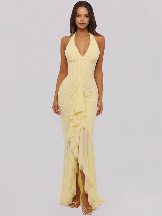 Woman wearing a yellow halter neck dress with ruffled details on a light gray background