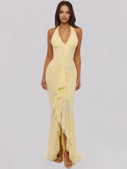 Woman wearing a yellow halter neck dress with ruffled details on a light gray background