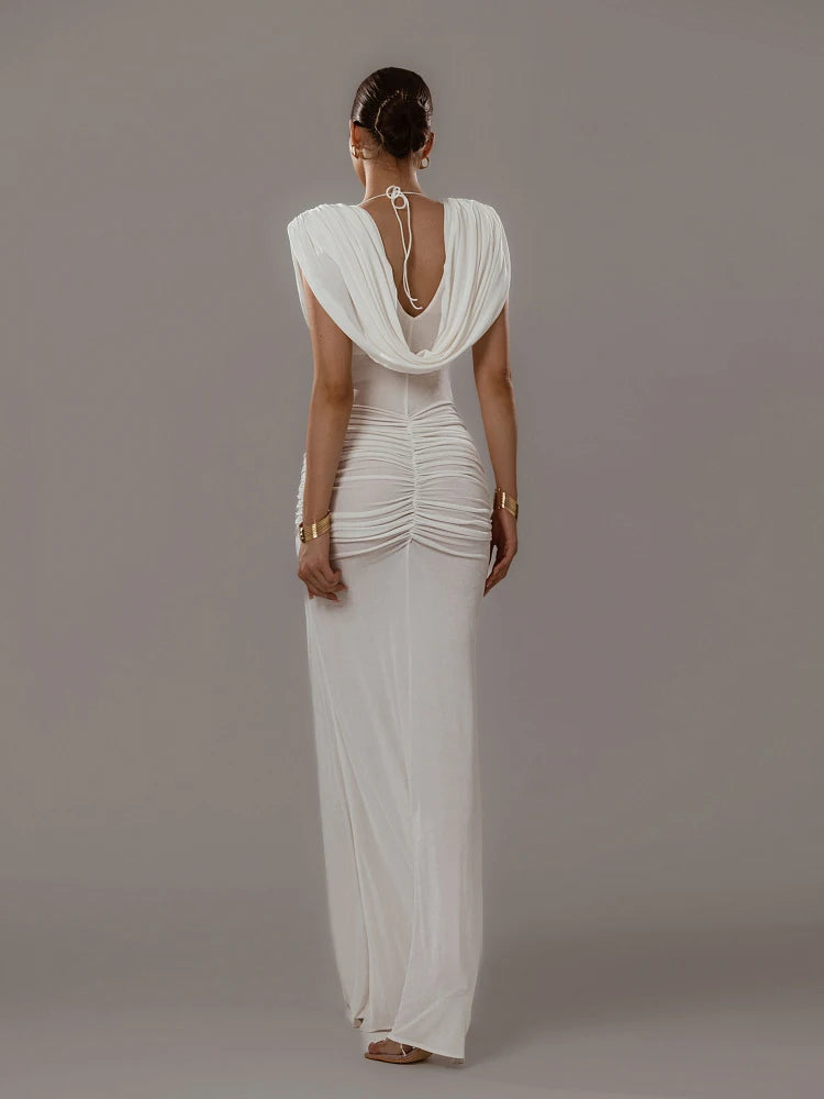 Woman wearing a white evening gown with a draped back design on a gray background