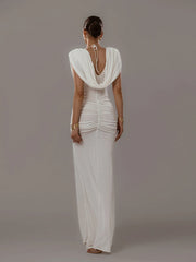 Woman wearing a white evening gown with a draped back design on a gray background