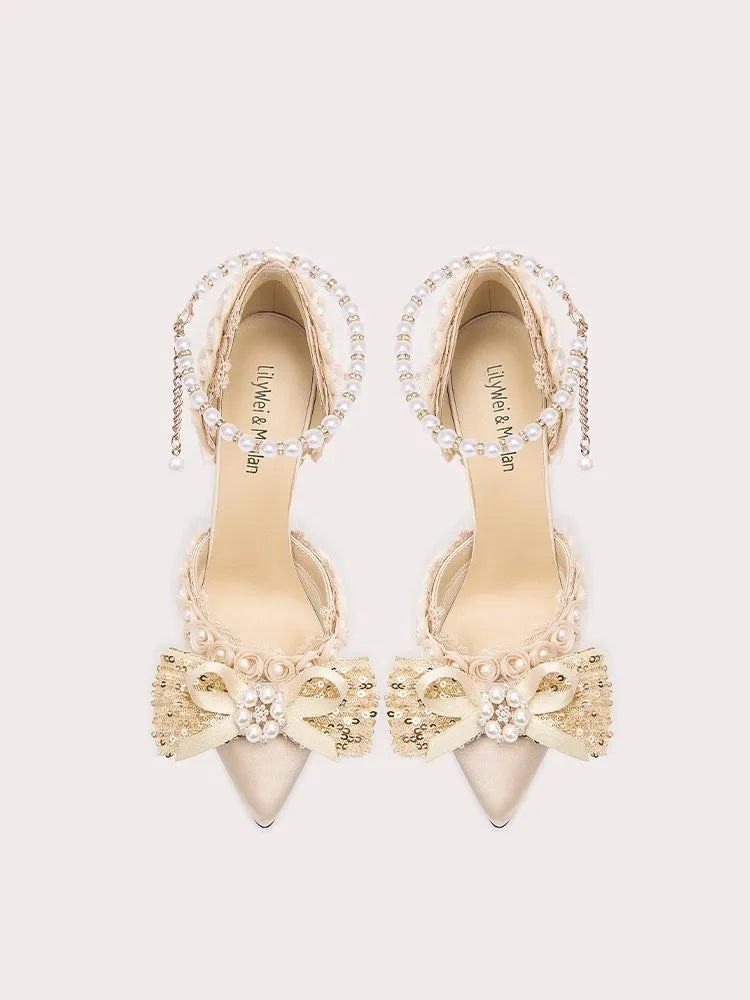 Pair of beige high-heeled shoes with decorative elements on a light gray background