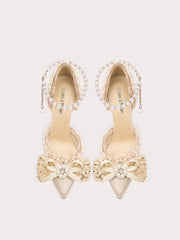 Pair of beige high-heeled shoes with decorative elements on a light gray background