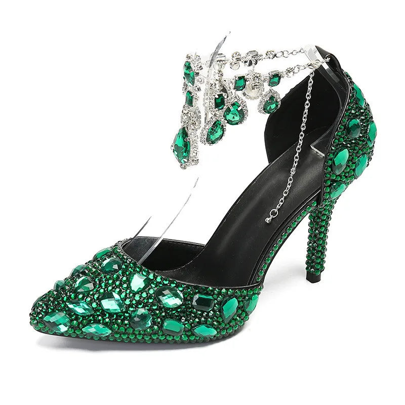 Green jeweled high-heeled shoe with decorative anklet on a white background