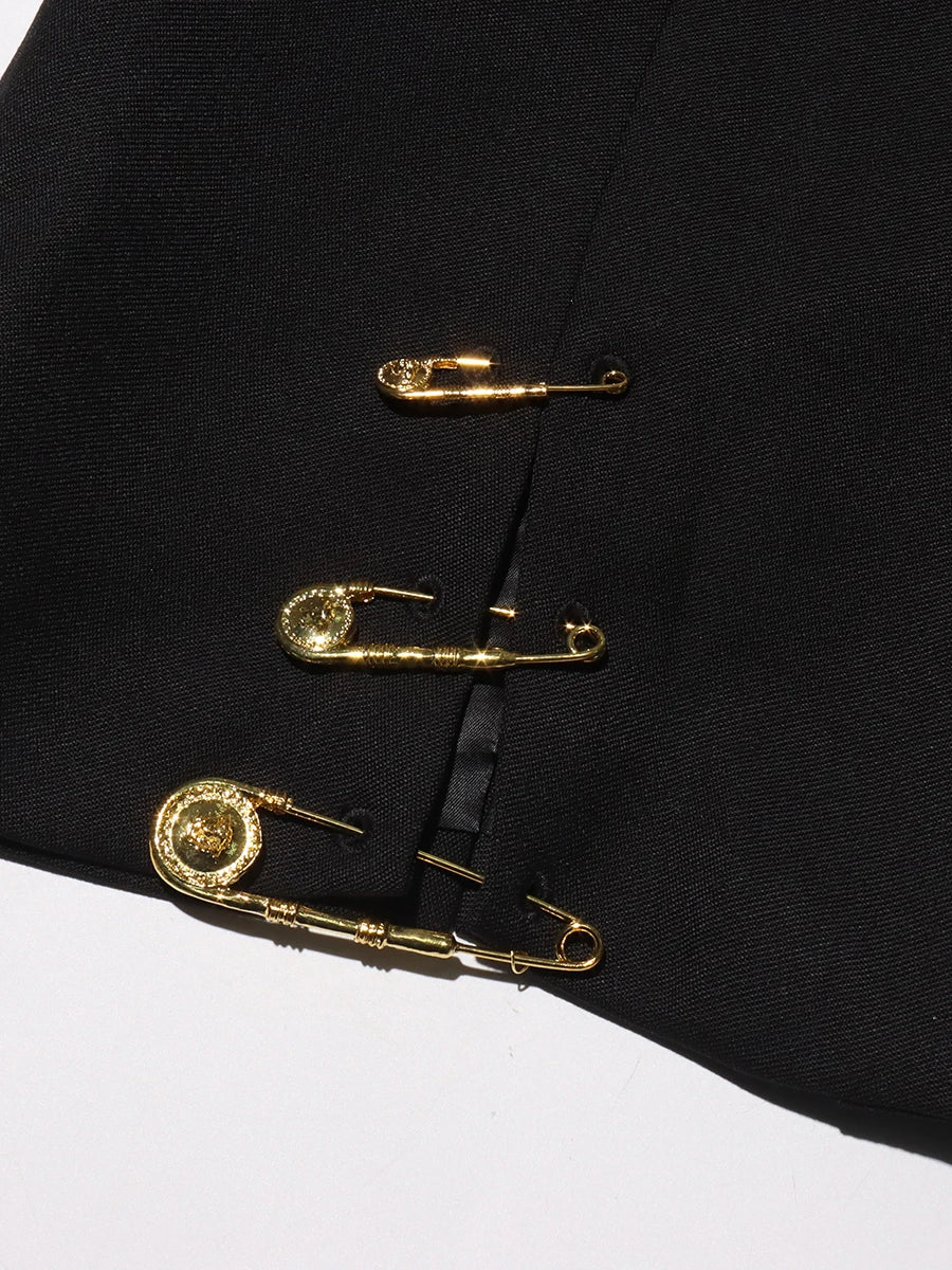 Black fabric with gold safety pins on a white background