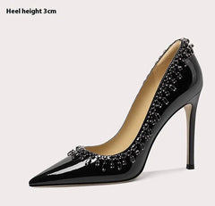 Black high-heeled shoe with decorative elements on a light gray background