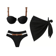 Black bikini set with leather straps and a white accent band on bottoms, accompanied by a black wrap skirt.