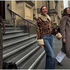 Two women standing on a city street, one wearing a leopard print coat with fur trim.