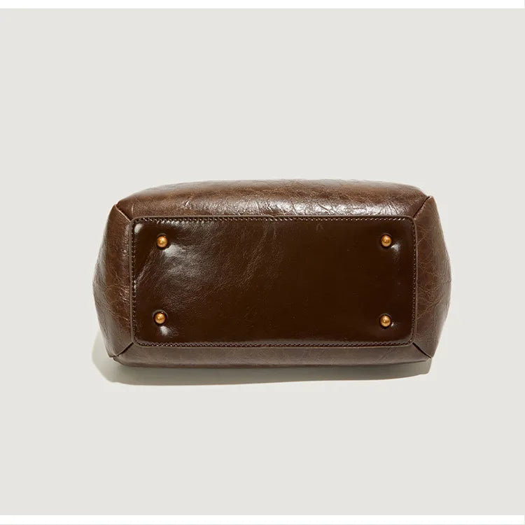 Brown leather bag with gold studs on a light gray background